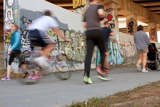 People walking and biking under a bridge along the Atlanta Beltline path